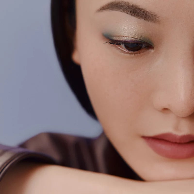 Close-up of a person's face with soft makeup against a neutral background